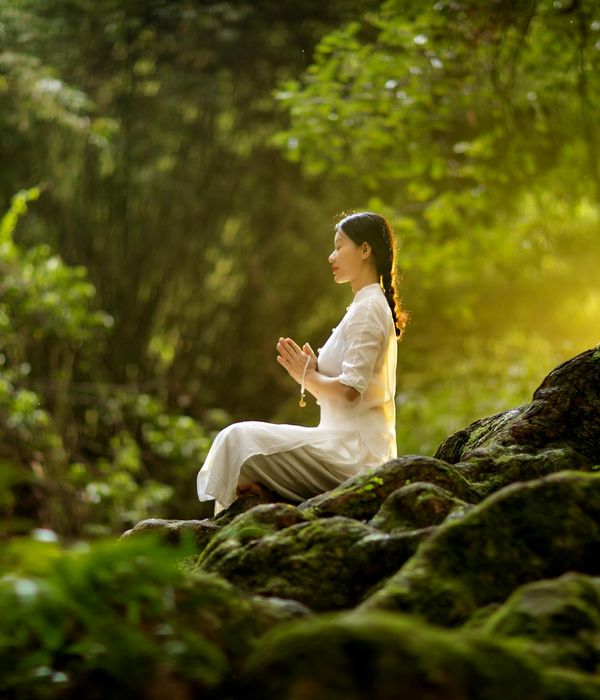 Woman holding a calm yoga pose in a dark, serene environment.